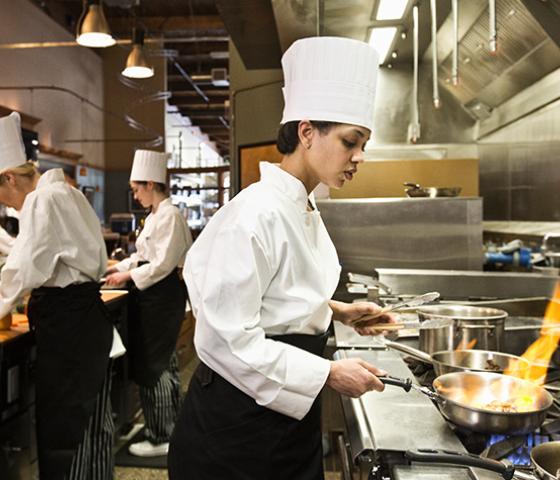 Image of a person using a wok in a commercial kitchen 