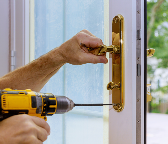 Image of a person drilling a screw into a gold door handle 