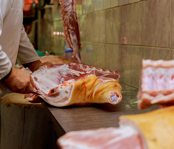 Image of meat carcass on a sterile bench being cut up by a person 