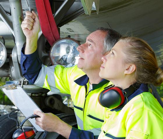 Image of 2 aero skills mechanics looking at part attached to the plane tire 
