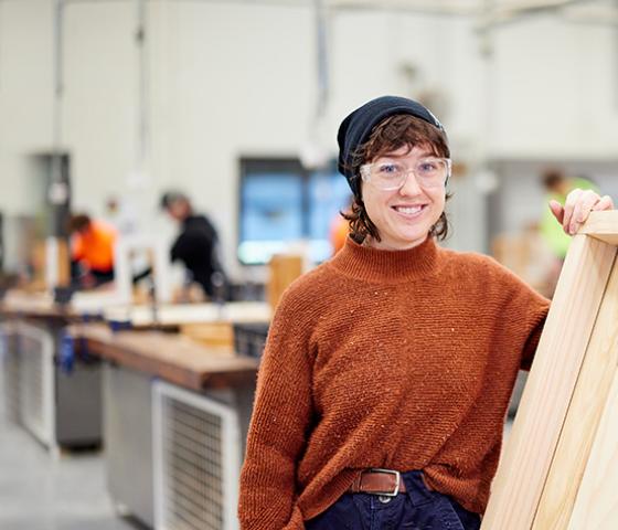 Image of a TAFE student standing with a wooden board 