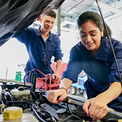 Female and male mechanic fixing car 