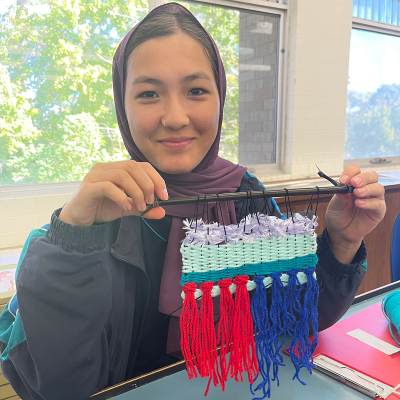 Student sitting at desk with a knitted project 