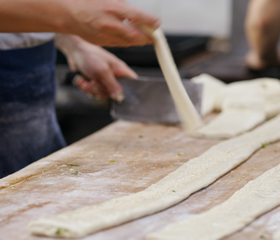 Image of long lengths of pastry being laid out on a kitchen bench