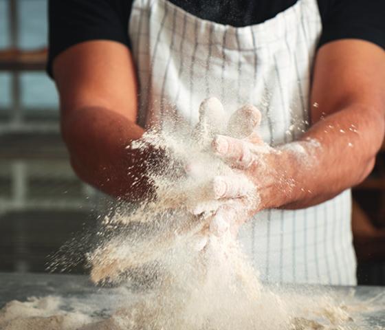 Image of a person wearing an apron working with flour 