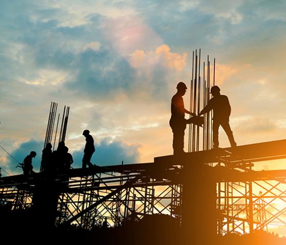 Image of builders on a construction site at sunset 