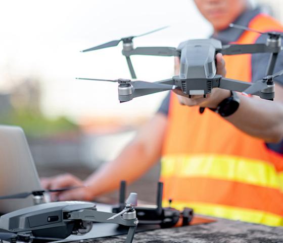 Image of a person wearing a hivis vest holding a drone. 