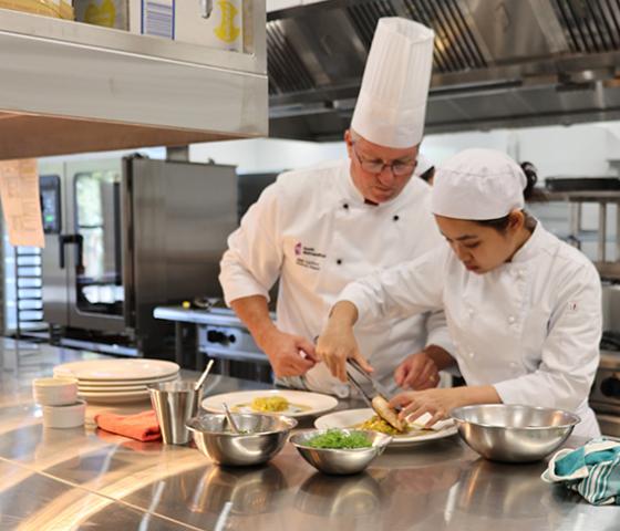 image of hospitality supervisor and chef preparing food