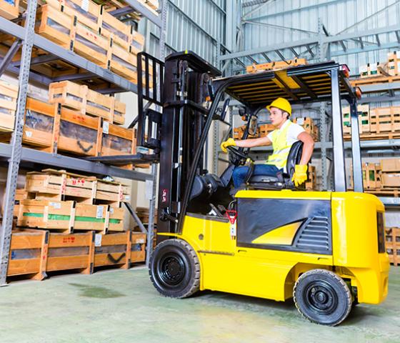 Person operating forklift, putting a pallet away on a high shelf